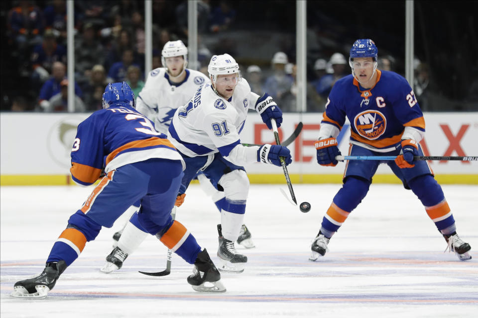 Tampa Bay Lightning's Steven Stamkos (91) passes the puck away from New York Islanders' Adam Pelech (3) and Anders Lee (27) during the first period of an NHL hockey game Friday, Nov. 1, 2019, in Uniondale, N.Y. (AP Photo/Frank Franklin II)