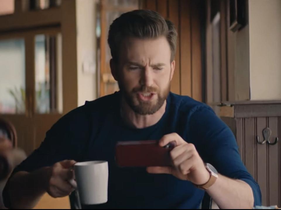 chris evans looking at his phone and drinking a coffee in free guy