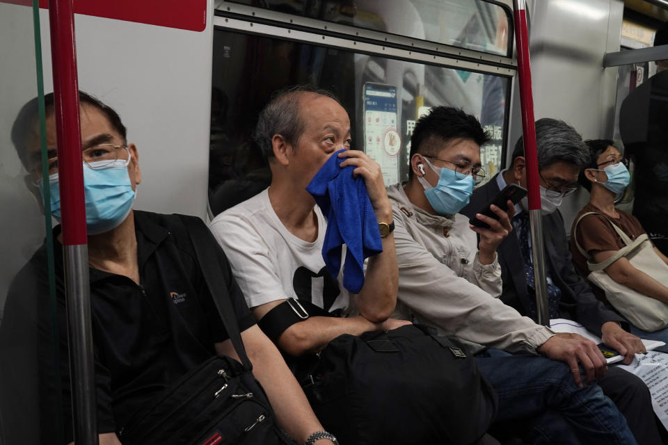 A passenger covers his nose and mouth with a towel to help protect himself against the coronavirus in a subway car in Hong Kong, Friday, Oct. 16, 2020. (AP Photo/Kin Cheung)