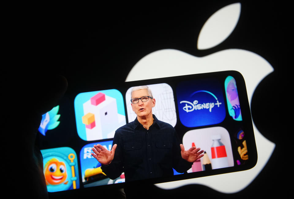 En esta ilustración fotográfica se ve al consejero delegado de Apple, Tim Cook, en la pantalla de un teléfono móvil durante una Conferencia Mundial de Desarrolladores de Apple (WWDC) en Cupertino, California, Estados Unidos, delante del logotipo de Apple al fondo. (Ilustración fotográfica de Pavlo Gonchar/SOPA Images/LightRocket vía Getty Images)