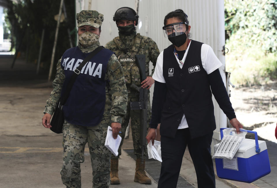 FILE - In this Feb. 24, 2021, file photo, a health worker is escorted by soldiers as she arrives to the Sports Center with a cooler containing doses of the Russian COVID-19 vaccine Sputnik V, for a mass vaccination campaign against the new coronavirus for the elderly in the Xochimilco borough of Mexico City. The stark vaccine access gap is prompting increased calls across the world for the U.S. to start shipping vaccine supplies to poorer countries. (AP Photo/Marco Ugarte, File)