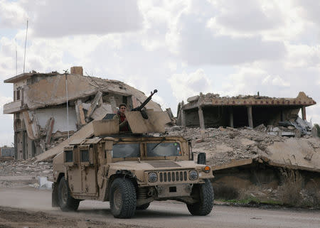 FILE PHOTO: A fighter from the Syrian Democratic Forces (SDF) rides on a vehicle in the village of Baghouz, Deir Al Zor province, Syria, February 18, 2019. REUTERS/Rodi Said/File Photo