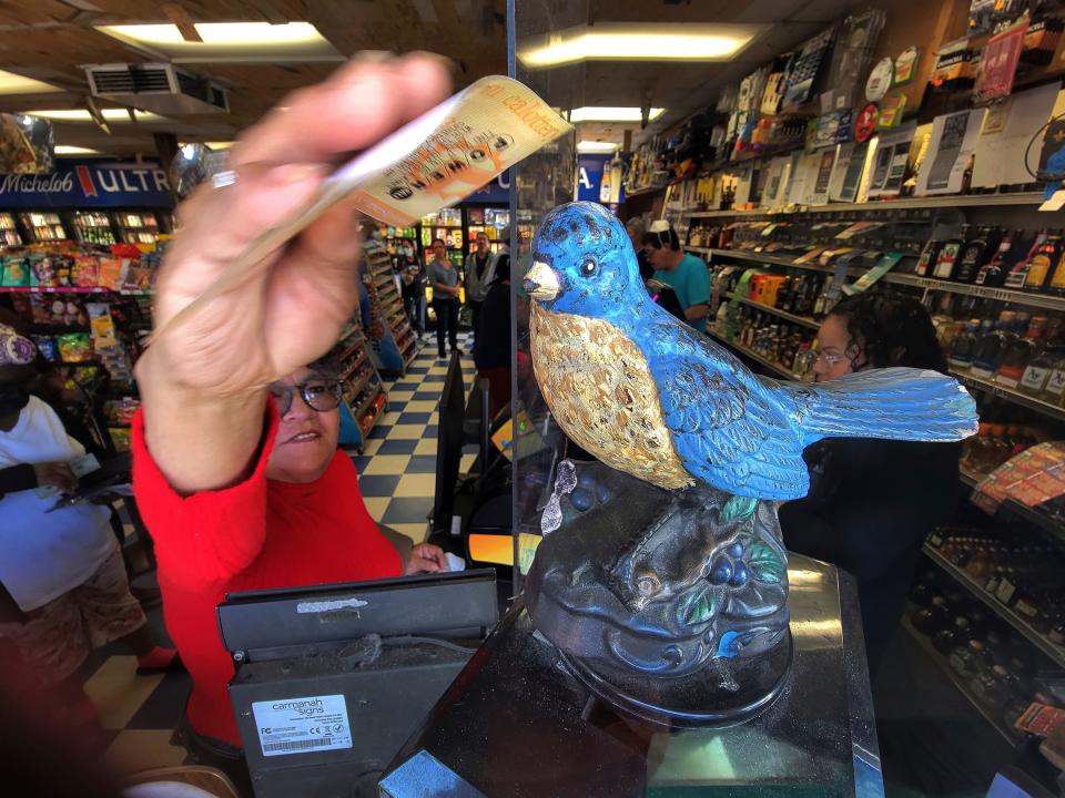 A customer rubs her Powerball tickets on the head of a lucky bluebird statue at the Bluebird Liquor store in Hawthorne, Calif., Saturday, Nov. 5, 2022.