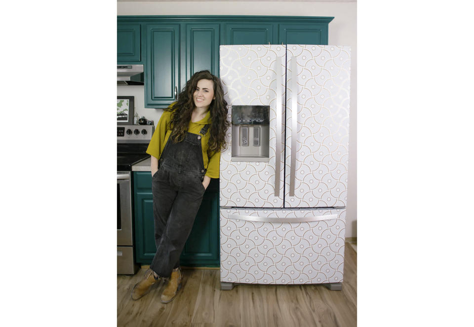 Designer Liz Morrow stands next to her refrigerator covered with a stylish patterned Tempaper removable paper at her home in Tacoma, Wash. (Liz Morrow via AP)