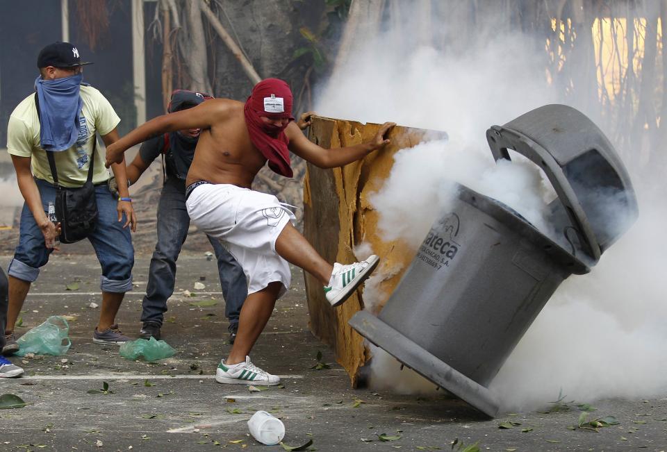 Demonstrators confront police after a tear gas grenade fell into a trash can, during a protest against the government of President Nicolas Maduro in Caracas, February 22, 2014. A female student and a young supermarket worker were the latest fatalities from Venezuela's political unrest as the death toll from 10 days of violence rose on Saturday to at least eight. REUTERS/Carlos Garcia Rawlins (VENEZUELA - Tags: CIVIL UNREST POLITICS)