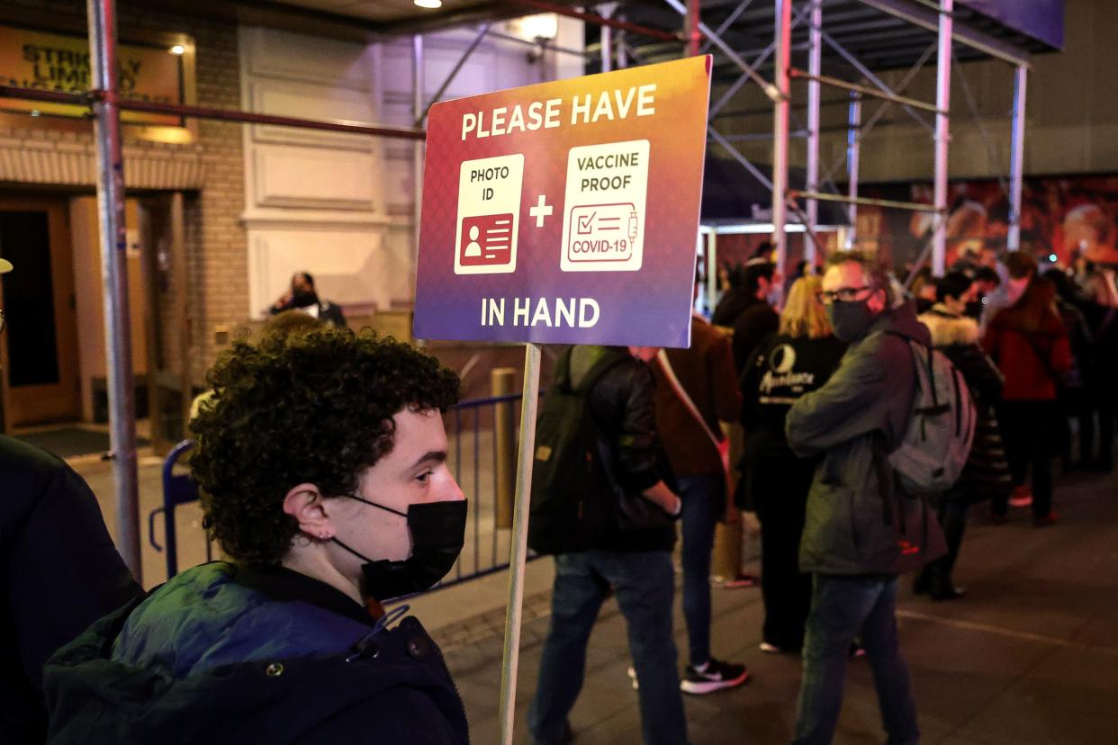 A worker holds a COVID protocol sign for guests attending the evening performance of "Freestyle Love Supreme" at the Booth Theatre on Dec. 16. 