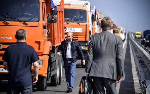 Russian President Vladimir Putin walks away from a construction truck after driving the vehicle across the new bridge - Credit: Alexander Nemenov/AFP