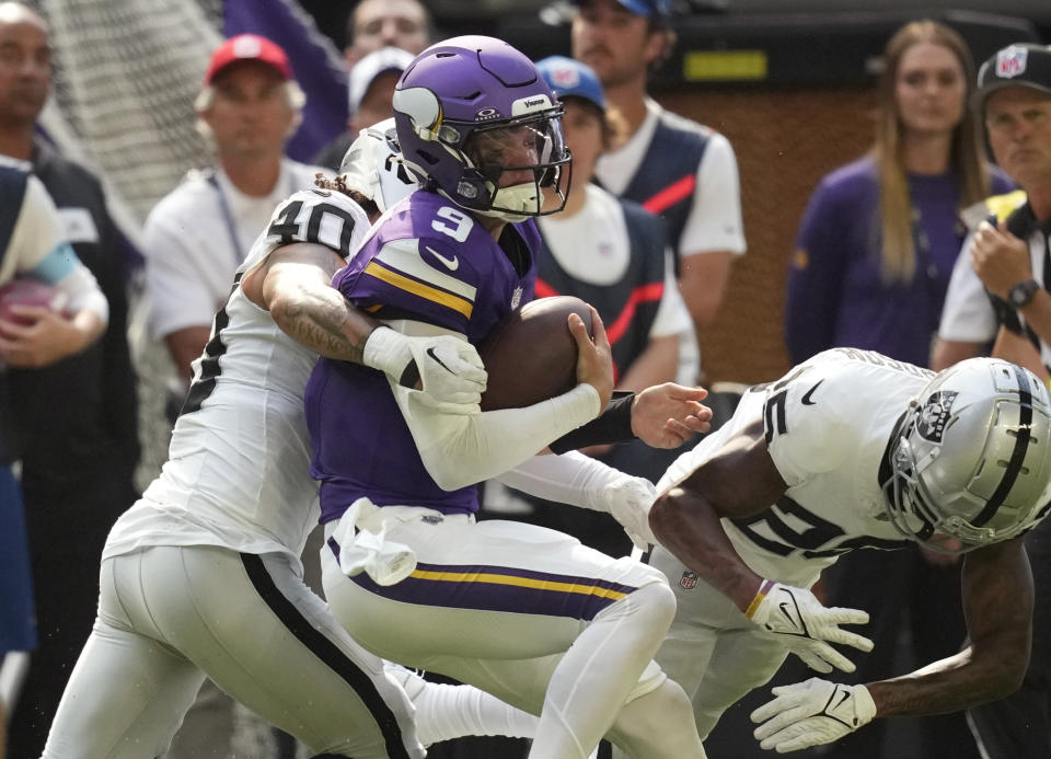 Minnesota Vikings quarterback J.J. McCarthy (9) is hit by Las Vegas Raiders safety Jaydon Grant (40) as he scrambles for yards during the first half of an NFL football game Saturday, Aug. 10, 2024, in Minneapolis. (AP Photo/Charlie Neibergall)