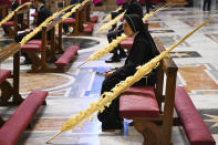 A nun sitting by a palm branch attends the Pope's Palm Sunday Mass behind closed doors in St. Peter's Basilica, at the Vatican, Sunday, April 5, 2020, during the lockdown aimed at curbing the spread of the COVID-19 infection, caused by the novel coronavirus. (AP Photo/pool/Alberto Pizzoli)