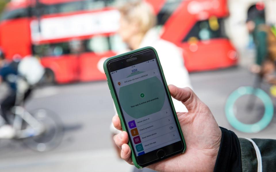 A smartphone displays a screen from the newly released 'NHS COVID-19' contract tracing app in view of traffic in this arranged photograph in London, U.K. - Simon Dawson/Bloomberg