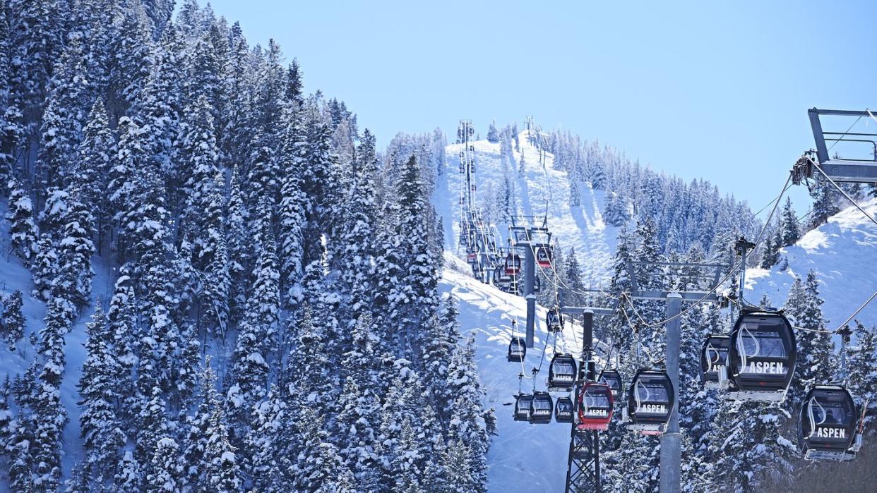 cable car moving up over forested snow covered mountains, aspen, colorado, usa