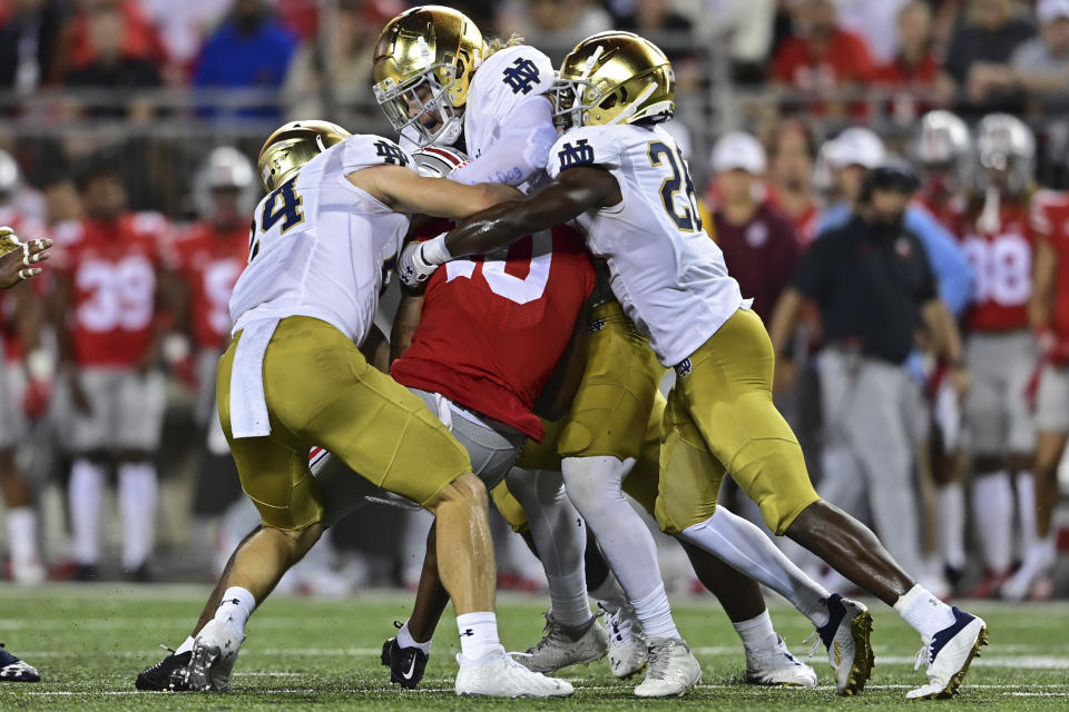 Ohio State wide receiver Xavier Johnson, center, is tackled by Notre Dame cornerback TaRiq Bracy, right, linebacker Bo Bauer, top, and linebacker Jack Kiser during the third quarter of an NCAA college football game Saturday, Sept. 3, 2022, in Columbus, Ohio. (AP Photo/David Dermer)
