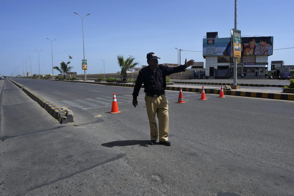 A police officer gestures to commuters for alternate route at a barricaded road leading to Clifton beach which closed for public due to high tide as Cyclone Biparjoy approaching, in Karachi, Pakistan, Monday, June 12, 2023. India and Pakistan are bracing for the first severe cyclone this year expected to hit their coastal regions later this week, as authorities halted fishing activities and deployed rescue personnel. (AP Photo/Fareed Khan)