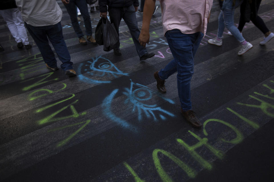 Pedestrian walks on a street painted with graffiti in reference to the International Women's Day strike "A Day Without Women" in Mexico City, Monday, March 9, 2020. Thousands of women across Mexico went on strike after an unprecedented number of girls and women hit the streets to protest rampant gender violence on International Women's Day. (AP Photo/Fernando Llano)