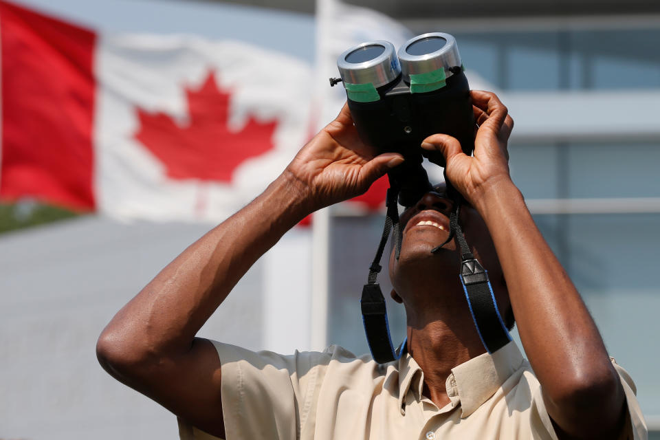 A man uses binoculars to watch a partial solar eclipse at the Canada Aviation and Space Museum in Ottawa, Ontario, Canada, August 21, 2017. REUTERS/Chris Wattie