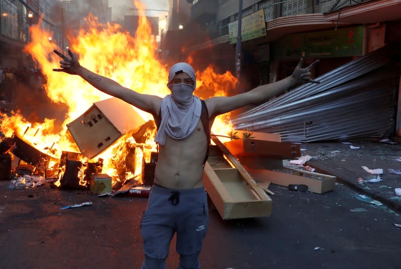 Un manifestante, frente a una barricada en llamas junto a una tienda saqueada durante una protesta contra el gobierno en Valparaíso, en Chile.