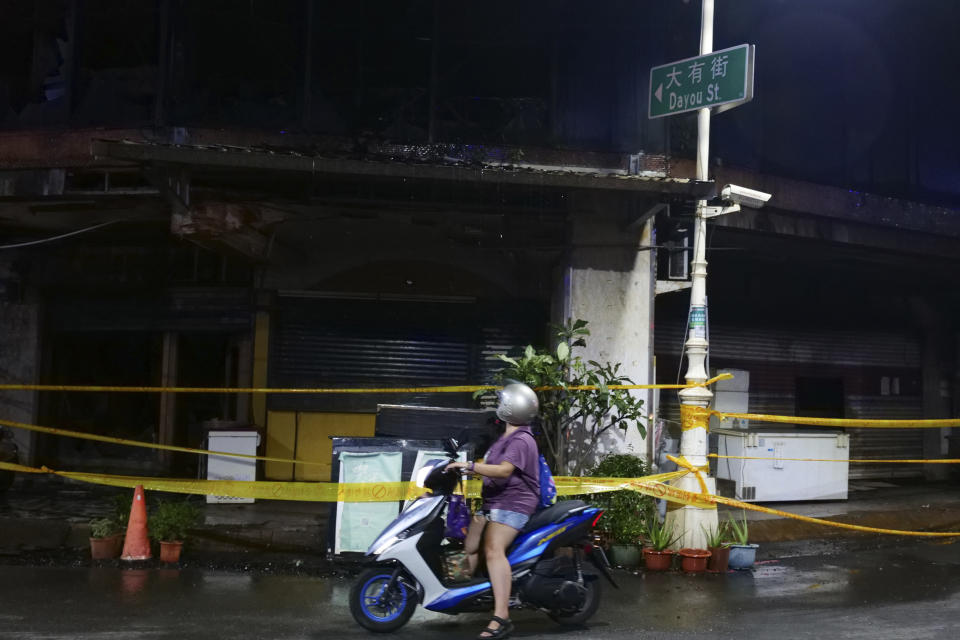 A woman looks passes a building after a fire, in Kaohsiung, southern Taiwan, Thursday, Oct. 14, 2021. Officials say at least 46 people were killed and over 40 injured after a fire broke out in a decades-old mixed commercial and residential building in the Taiwanese port city of Kaohsiunging. Neighborhood residents say the 13-story building was home to many poor, elderly and disabled people and it wasn’t clear how many of the 120 units were occupied. (AP Photo/Huizhong Wu)