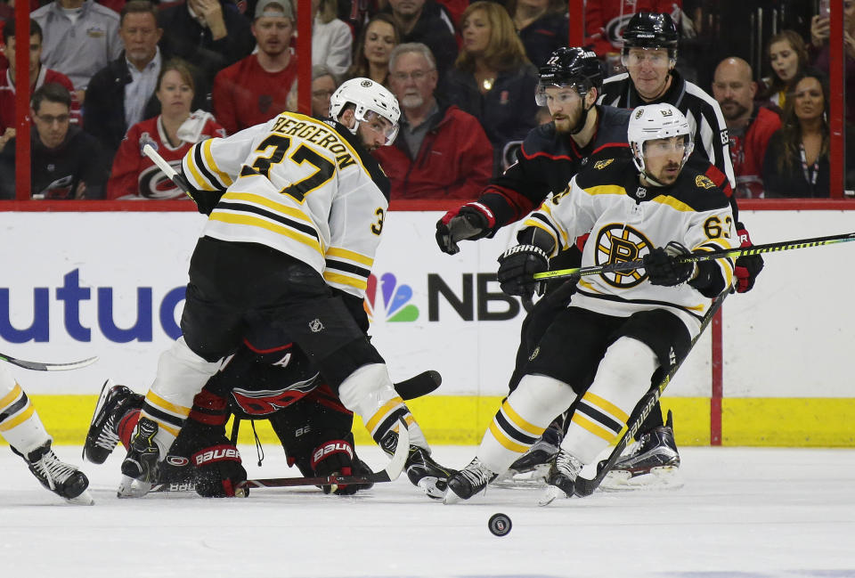 Boston Bruins' Patrice Bergeron (37) and Brad Marchand (63) skate for the puck with Carolina Hurricanes' Brett Pesce (22) and Jordan Staal during the second period in Game 3 of the NHL hockey Stanley Cup Eastern Conference final series in Raleigh, N.C., Tuesday, May 14, 2019. (AP Photo/Gerry Broome)