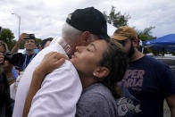 Rachel Spiegel, right, is hugged by the Mayor of Surfside Charles Burkett, left, as she asks for information about the 12-story beachfront condo building which partially collapsed, Saturday, June 26, 2021, in the Surfside area of Miami. Spiegel's mother Judy lives in the building and is missing. (AP Photo/Lynne Sladky)