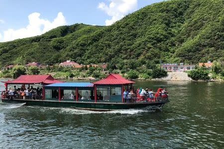 Chinese tourists are seen on a boat taking them from the Chinese side of the Yalu River for sightseeing close to the shores of North Korea, near Dandong, Liaoning province, China August 10, 2017. REUTERS/Philip Wen/Files