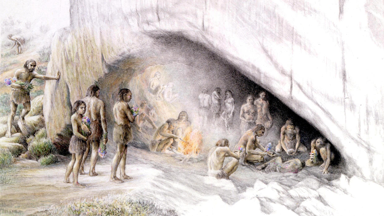  We see an illustration of neanderthals at the entrance of a cave holding flowers for a burial. 