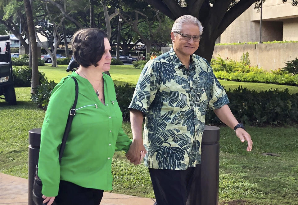 FILE - In this March 12, 2019 file photo, retired Honolulu police chief Louis Kealoha and his wife, former deputy city prosecutor Katherine Kealoha, hold hands while walking to U.S. district court in Honolulu. Opening statements are expected Wednesday, May 22, 2019, after 12 jurors and five alternates are selected for the trial of retired Honolulu police chief Louis Kealoha, his wife and current and former officers. Prosecutors say Kealoha and his former city deputy prosecutor wife, Katherine Kealoha, abused their power to frame a relative for stealing their home mailbox because he threatened to expose financial fraud that funded the couple's lavish lifestyle. (AP Photo/Jennifer Sinco Kelleher, File)