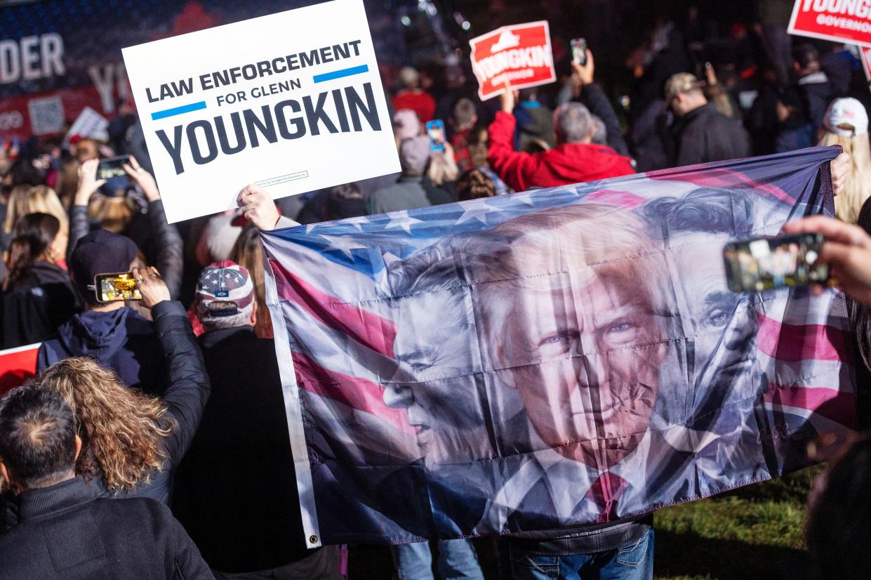 A supporter of Republican gubernatorial candidate Glenn Youngkin displays a flag showing Presidents Donald Trump, Ronald Reagan and Abraham Lincoln at a  rally in Leesburg, Va., on Nov. 1, 2021.