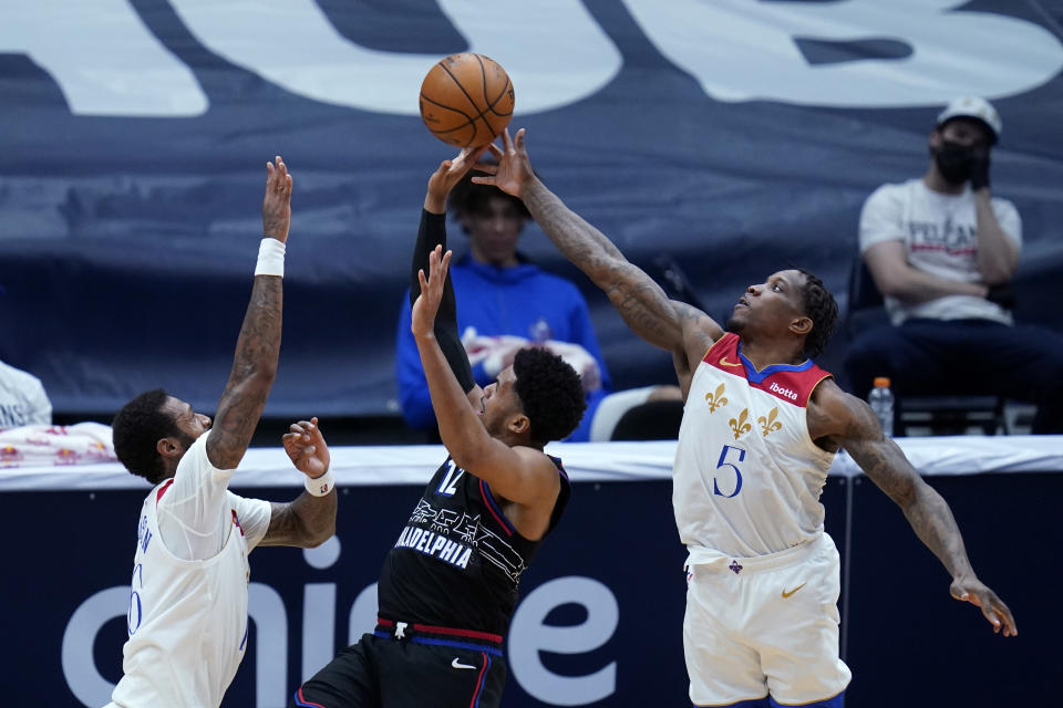 Philadelphia 76ers forward Mike Scott (12) shoots between New Orleans Pelicans guard Eric Bledsoe (5) and forward James Johnson in the second half of an NBA basketball game in New Orleans, Friday, April 9, 2021. (AP Photo/Gerald Herbert)