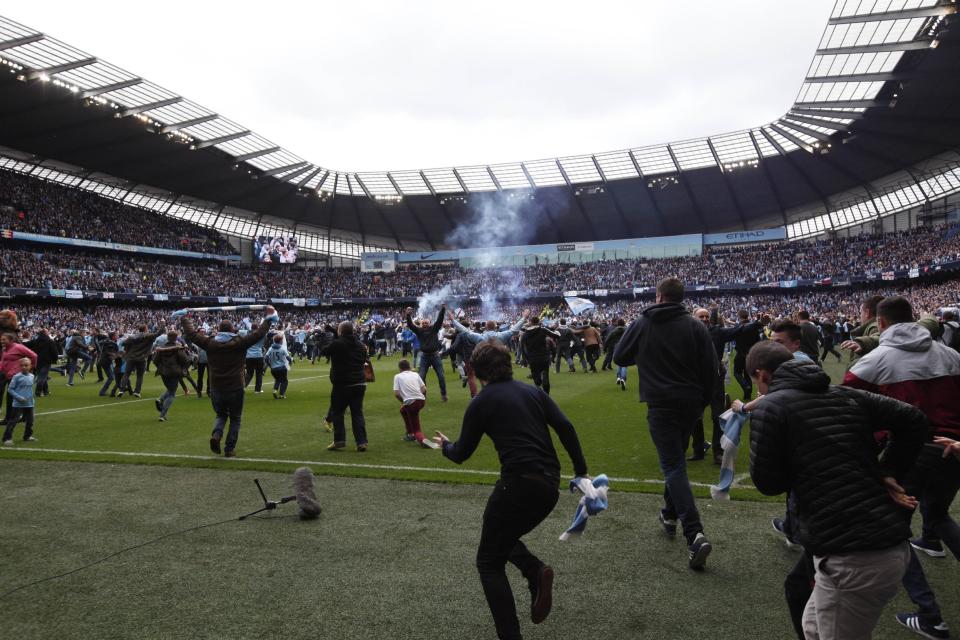 Manchester City fans invade the pitch at the end of their English Premier League soccer match between Manchester City and West Ham at the Etihad Stadium in Manchester, England, Sunday May 11, 2014. Manchester City won the Premier League for the second time in three seasons on Sunday, completing its campaign with a comfortable 2-0 victory over West Ham that lacked any of the drama of its previous title. (AP Photo/Jon Super)