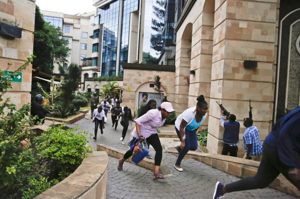 Civilians flee as security forces aim their weapons at a hotel complex attacked by al-Shabab extremists, in Nairobi, Kenya on Jan. 15, 2019. Facebook has failed to catch Islamic State group and al-Shabab extremist content in posts aimed at East Africa. (AP Photo/Khalil Senosi, File)