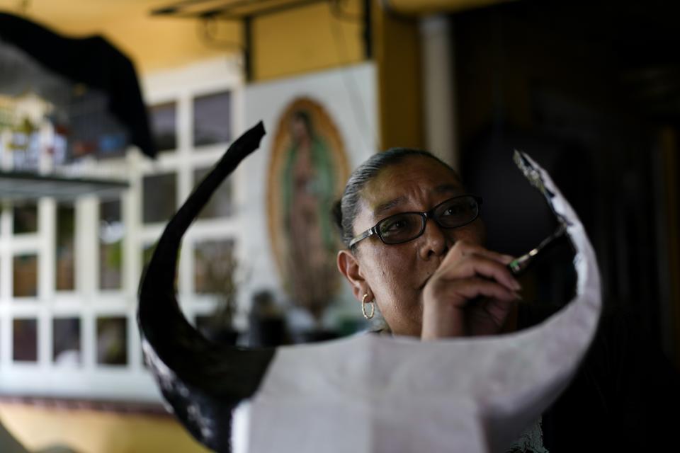 A member of the Cortes Miranda family paints a paper-mache bull that will be stuffed with fireworks in preparation for the annual festival in honor of Saint John of God, the patron saint of the poor and sick whom fireworks producers view as a protective figure, in Tultepec, Mexico, Tuesday, March 5, 2024. (AP Photo/Marco Ugarte)