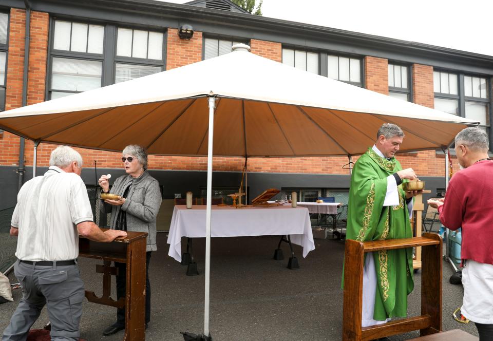 Communion is given during mass at St. Joseph Catholic Church on Wednesday, Sept. 20, 2023 in Salem, Ore. The church is still meeting outside after a fire severely damaged the church.