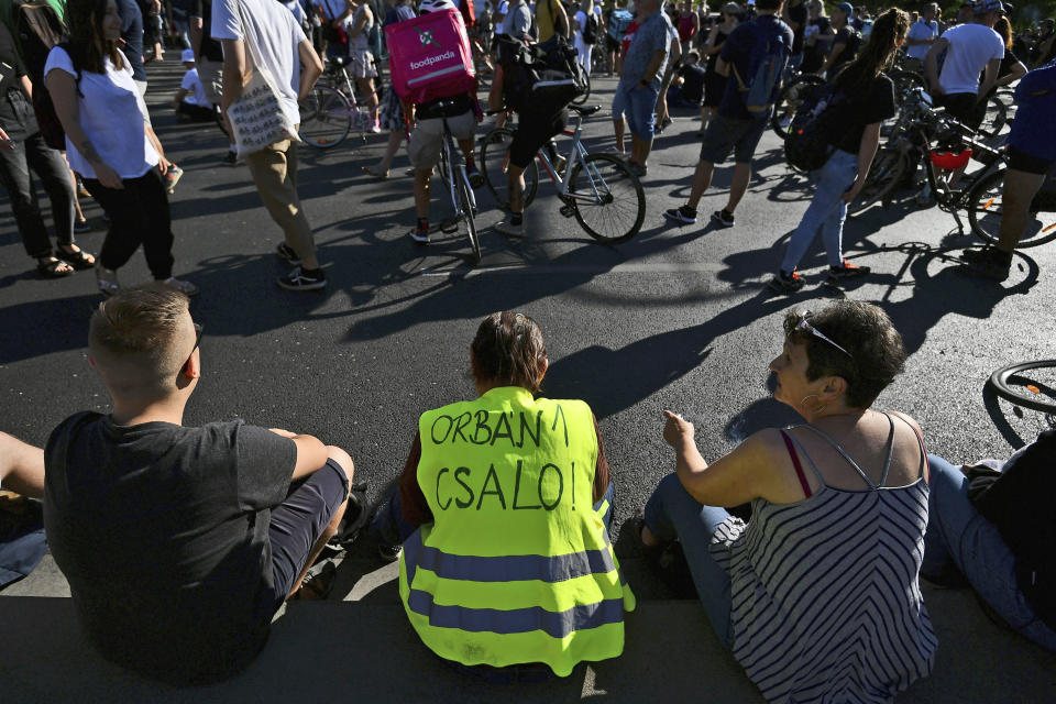 A demonstrator wears a vest with writing reading "Orban is a cheater" during an anti-government protest, in Budapest, Hungary, Monday, July 18, 2022. Anti-government demonstrators in Hungary blocked one of the capital's main thoroughfares during morning rush-hour traffic Monday, the latest in a series of protests against recent changes to the country's tax code that have carried on for nearly a week. (AP Photo/Anna Szilagyi)