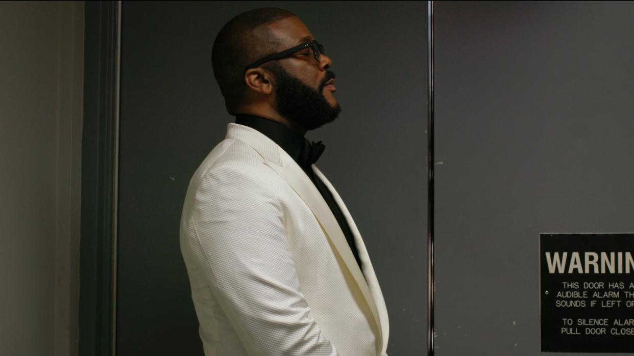  Tyler Perry standing next to a door in Maxine’s Baby: The Tyler Perry Story. 