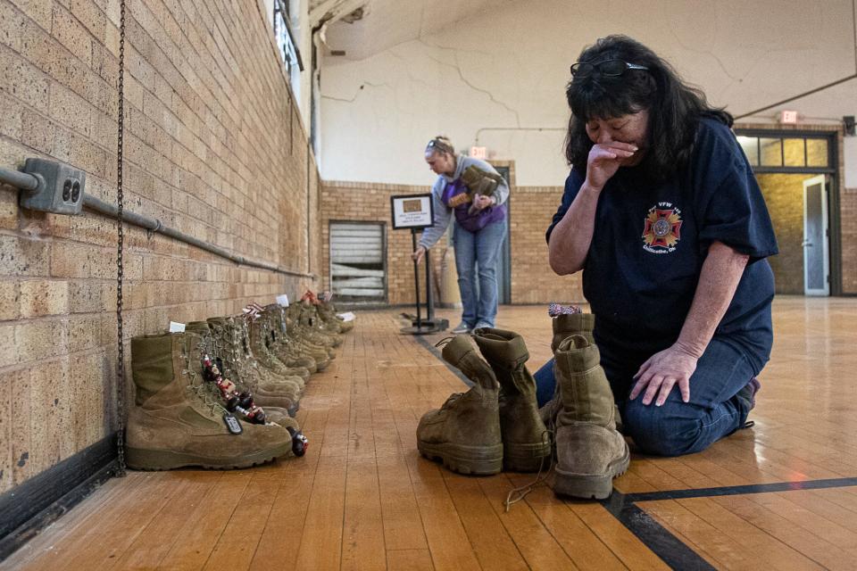 Johna Pulver becomes emotional as she arranges the boots of fallen soldiers for the Eyes of Freedom display is set up in the armory at Yoctangee Park in 2021. The Eyes of Freedom exhibit honors those men lost in Operation Iraqi Freedom.