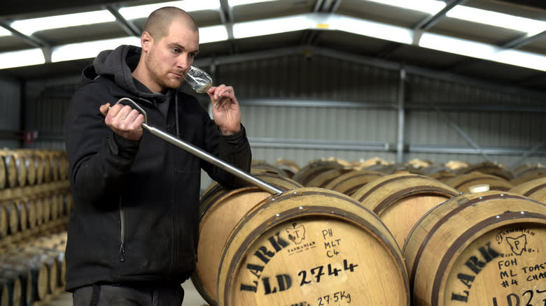 Man smells whiskey sample glass