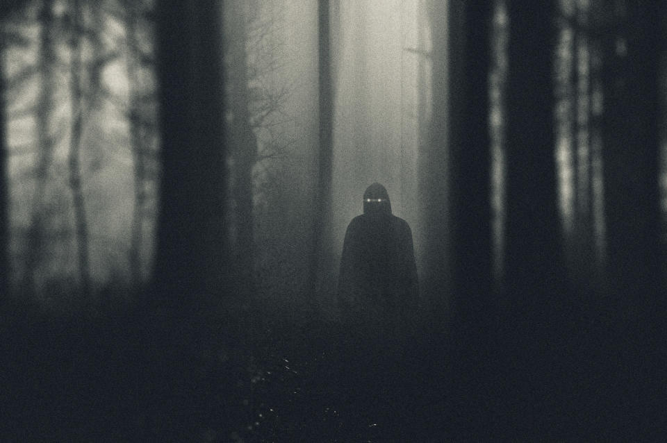 A yellow-eyed figure in the woods at night