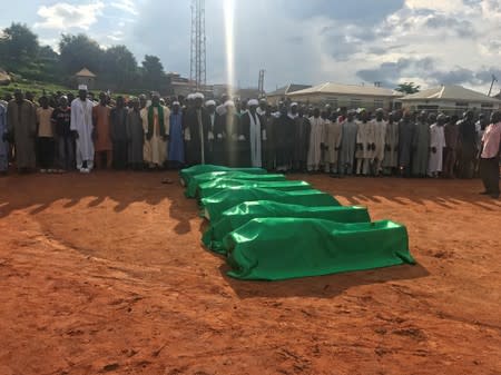 Members of a Shi'ite Muslim group gather to pray over the bodies of those who died during clashes with the police in Suleja