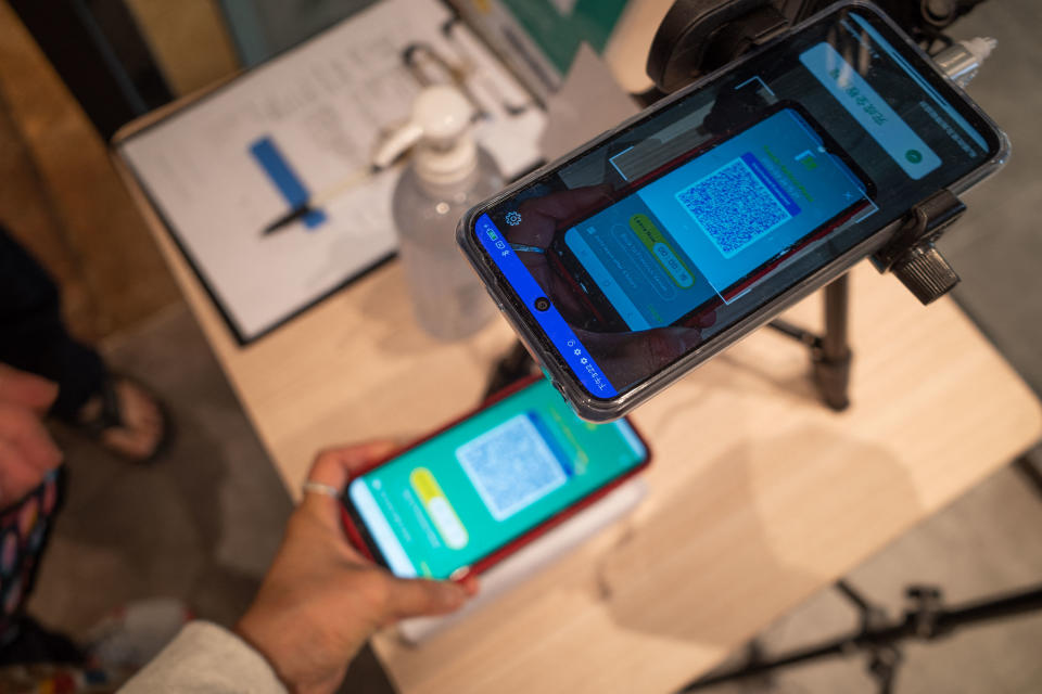 A woman scans a QR code for the government's Covid-19 vaccine pass at a restaurant in Hong Kong on February 26, 2022. (Photo by Bertha WANG / AFP) (Photo by BERTHA WANG/AFP via Getty Images)