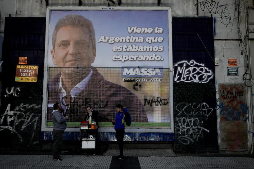 La gente compra café frente a un cartel de campaña del ministro de Economía y aspirante presidencial Sergio Massa en Buenos Aires, Argentina, el martes 14 de noviembre de 2023. (AP foto/Natacha Pisarenko)