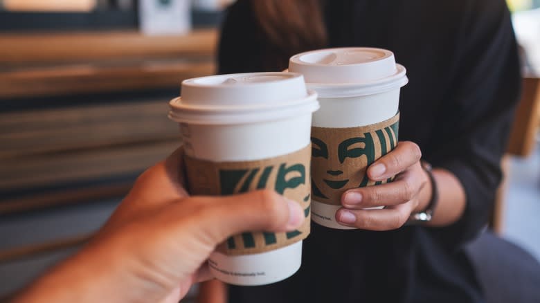 two hands holding Starbucks cups