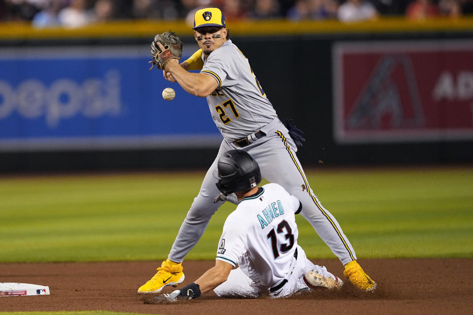 Milwaukee Brewers' Willy Adames (27) loses the ball after forcing out Arizona Diamondbacks' Nick Ahmed (13) while trying to turn a double play on Gabriel Moreno during the fourth inning of a baseball game, Monday, April 10, 2023, in Phoenix. Adames was charged with an error on the play. (AP Photo/Matt York)