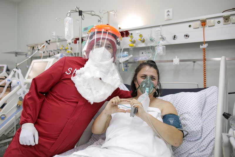 Ionut Ivan, a 40-year-old nurse, dressed in red Personal Protective Equipment (PPE) poses for a picture next to Brindusa Gheorghiu, in Bucharest