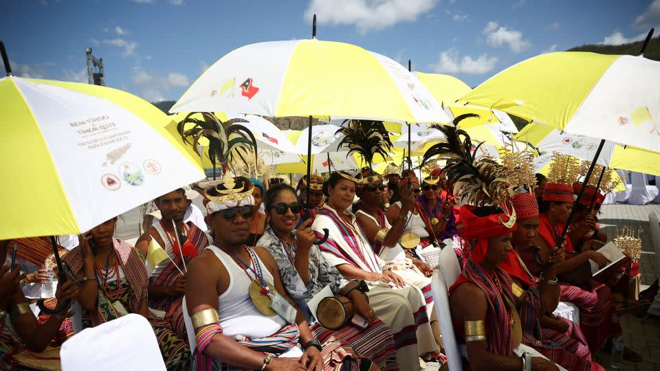 Crowds wait for the pope under yellow and white umbrellas. - Guglielmo Mangiapane/Reuters