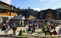 Tourists sit at outdoor cafes on a sunny day in Vlasic, a ski resort affected by unusual warm weather in Bosnia, Tuesday, Jan. 3, 2023. The exceptional wintertime warmth is affecting ski resorts across Bosnia, prompting tourism authorities in parts of the country to consider declaring a state of natural emergency. (AP Photo/Almir Alic)