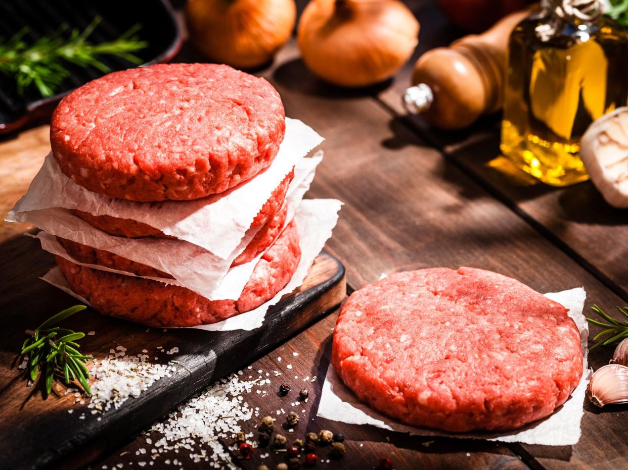 High angle view of raw patties for making burgers shot on rustic wooden kitchen table.