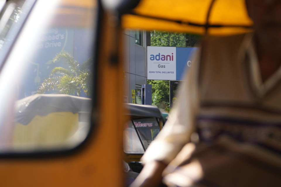 An autorickshaw driver waits for passengers in front of an Adani gas customer care centre in Ahmedabad, India, Feb. 2, 2023. Shares in Adani Enterprises tumbled 26% Thursday, while stock in six other Adani companies fell 5%-10%. Adani slid from being the world’s third richest man to the 13th as his fortune sank to $72 billion, according to Bloomberg’s Billionaire Index. (AP Photo/Ajit Solanki)