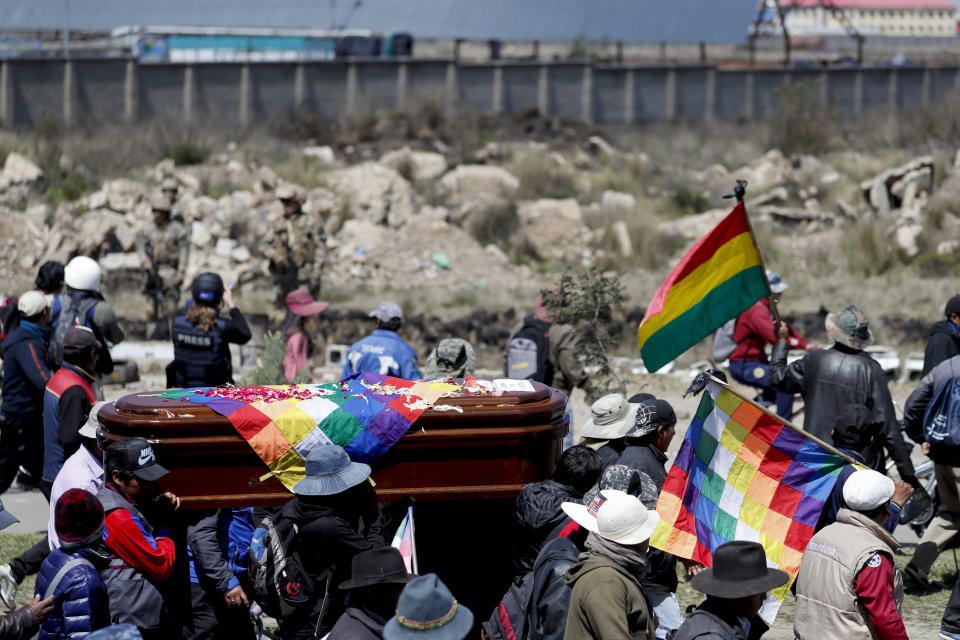 Los dolientes pasan junto a la planta de combustible de Senkata mientras llevan un ataúd que contiene los restos de una persona asesinada durante los enfrentamientos entre las fuerzas de seguridad y los manifestantes antigubernamentales en El Alto, Bolivia, el jueves 21 de noviembre de 2019. (AP Foto / Natacha Pisarenko)