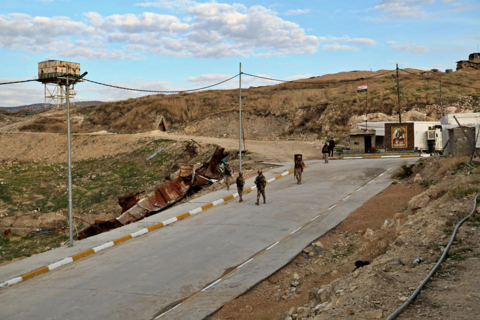 Iraqi army soldiers walk down the road leading to the Sayida Zeinab shrine in Sinjar, Iraq. Friday Dec. 4, 2020. A new agreement aims to bring order to Iraq's northern region of Sinjar, home to the Yazidi religious minority brutalized by the Islamic State group. Since IS's fall, a tangled web of militia forces have run the area, near the Syrian border. Now their flags are coming down, and the Iraqi military has deployed in Sinjar for the first time in nearly 20 years. (AP Photo/ Samya Kullab)