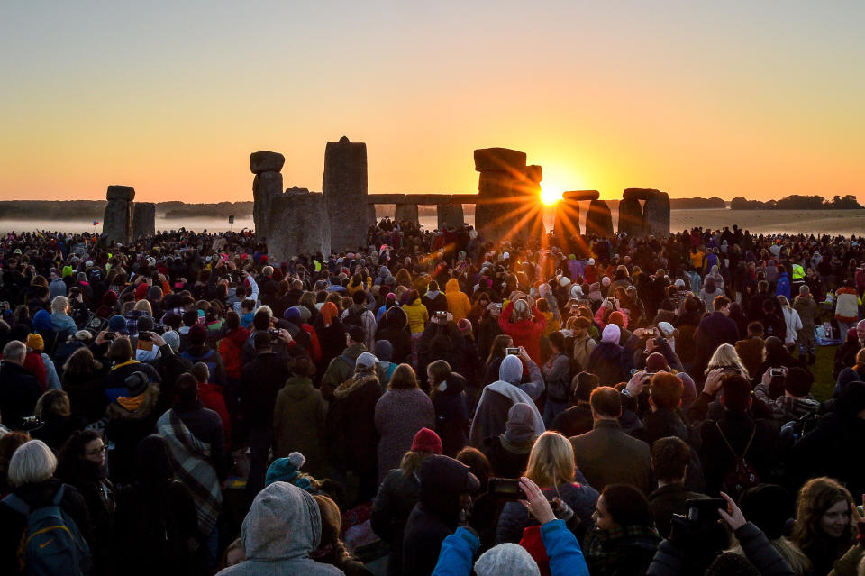 File photo dated 21/06/19 of the sun rising between the stones and over crowds gathered at Stonehenge to celebrate the dawn of the longest day in the UK. English Heritage - which has provided access to the summer solstice celebrations at Stonehenge since 2000 - has cancelled celebrations due to restrictions on mass gatherings to tackle Covid-19, and will instead stream the solstice online.